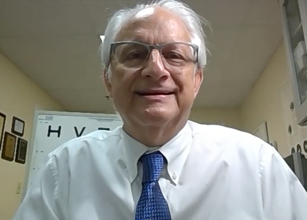 Dr. Scott Gartner, a low vision specialist, looks at camera wearing a white collared shirt and blue tie as he talks about the new eSight 4